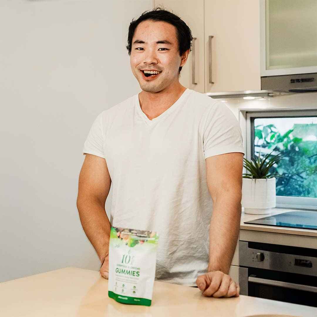 Happy man in kitchen eating a Jaje Superfood & Greens Gummy.